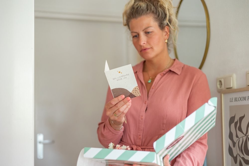 Vrouw leest wenskaart uit brievenbus cadeau