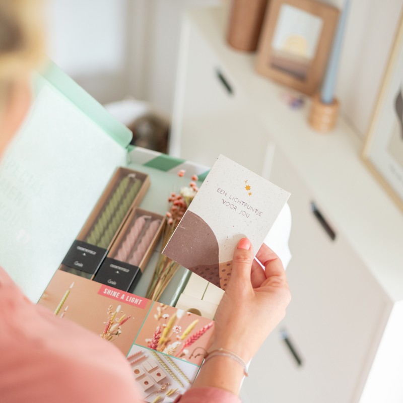 Vrouw heeft kaartje vast met tekst 'een lichtpuntje voor jou'