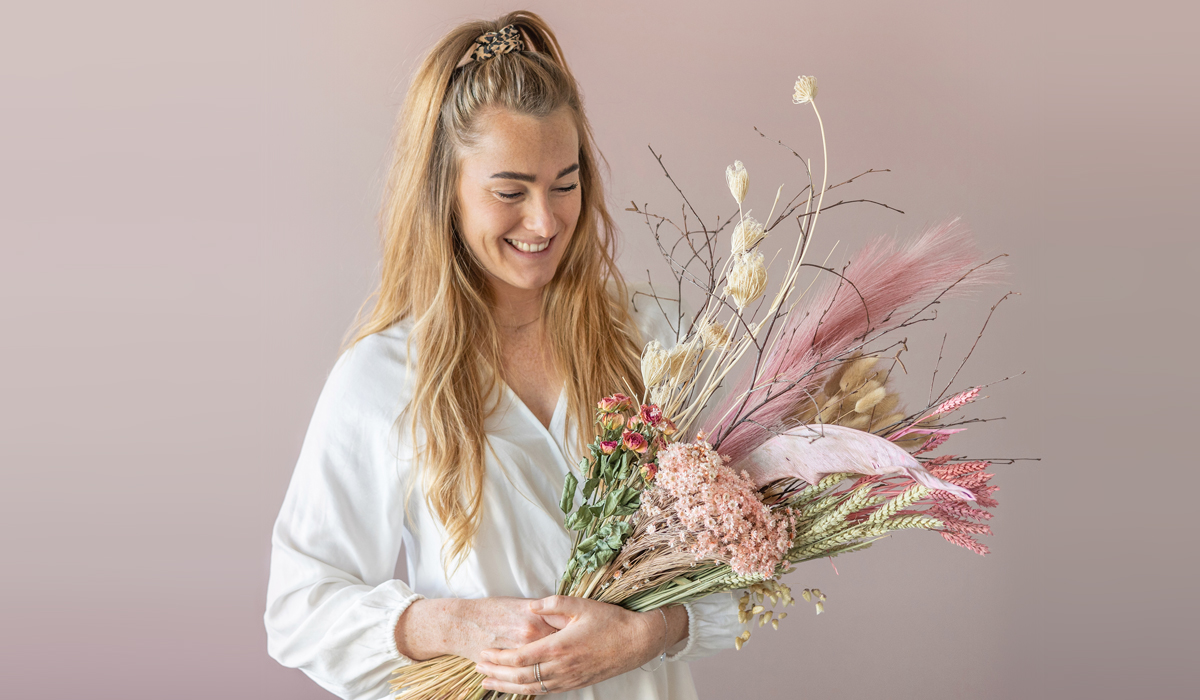 vrouw met bos droogbloemen in haar hand