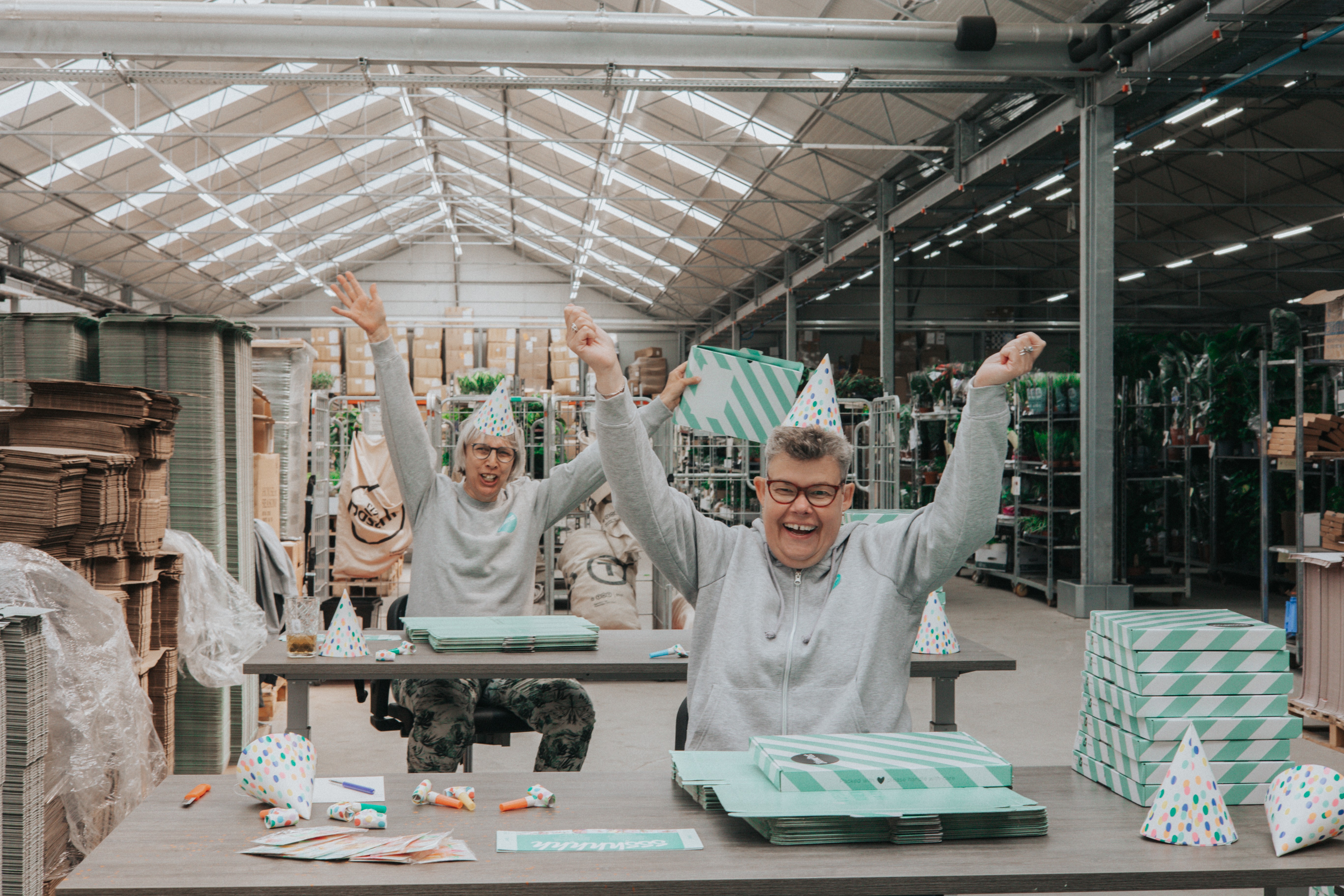 twee vrouwen met feesthoedjes en bloompost-doosjes