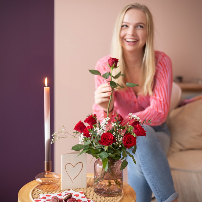 vrouw lacht met bosje rode rozen en hartjeskaart 