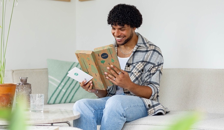 man bekijkt cadeau in brievenbus doosje